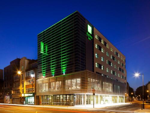 a building with a green sign on the side of it at Holiday Inn London - Whitechapel by IHG in London