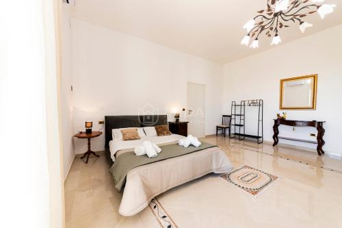 a white bedroom with a large bed and a chandelier at Dimora Due Mari in Salice Salentino