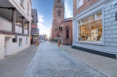 an empty street in a city with a clock tower at Central Two Bed Cottage on Watergate Street in Chester