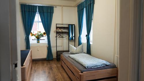 a bedroom with a bed with blue curtains and a window at Gwuni's Farm in Geithain