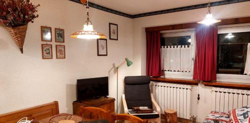 a living room with a television and red curtains at Dolce Vista in Passo del Tonale