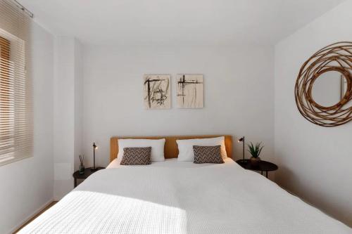 a white bedroom with a large bed and a mirror at Fewo Spectrum in Überlingen