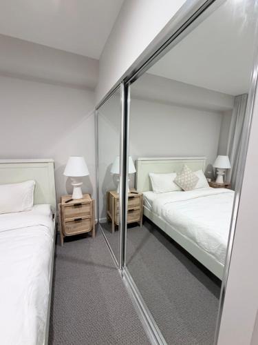 a bedroom with two beds and a mirror at 24 Bromley St private room in a luxurious shared apt in Brisbane