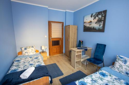 a bedroom with two beds and a desk and a chair at noclegi u zabki in Ełk