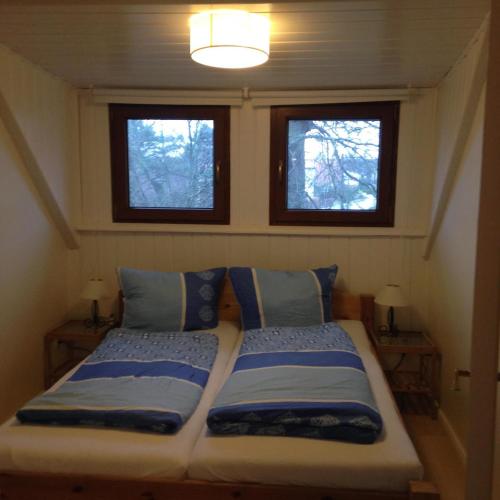 a bed in a small room with two windows at Ferienwohnung Klabautermann in Zinnowitz