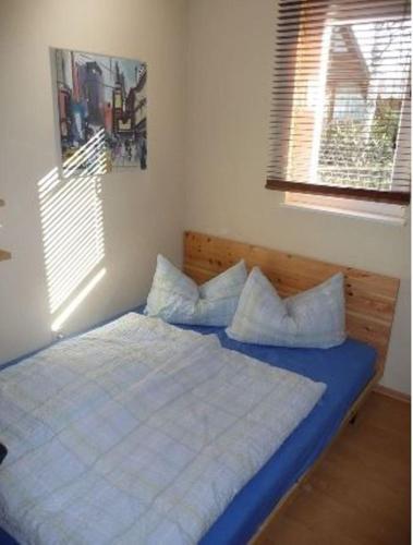 a bedroom with a bed with blue sheets and a window at Ferienhaus Alessandra in Zinnowitz