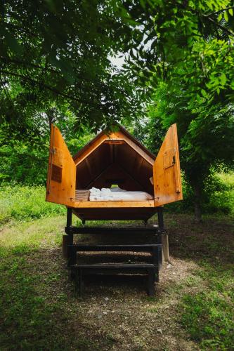 a wooden bed sitting in the grass under a tree at Agronidi Baladin StarsBox in Piozzo