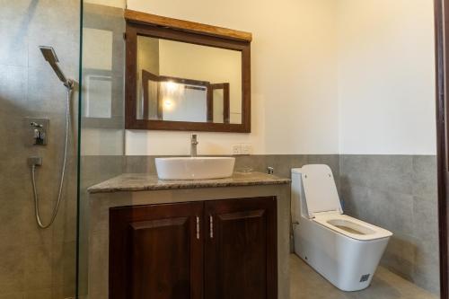 a bathroom with a sink and a toilet and a mirror at Surfside Serenity - SS Beach in Ahangama