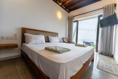 a bedroom with a large bed with a large window at Surfside Serenity - SS Beach in Ahangama