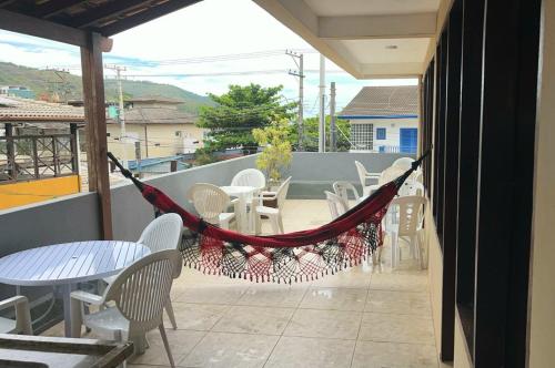 a hammock on a balcony with tables and chairs at Apartamento Vista ao Mar Maresias in Maresias