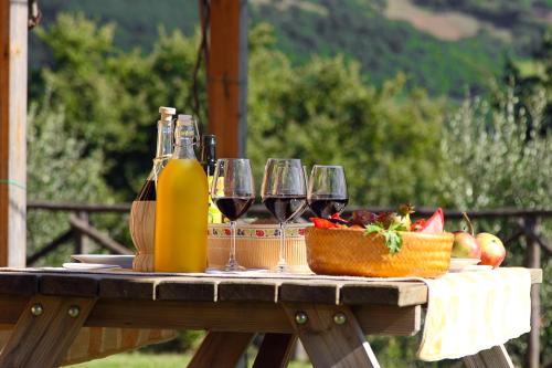 a table with glasses of wine and a basket of fruit at Agriturismo La Coccinella in Valfabbrica