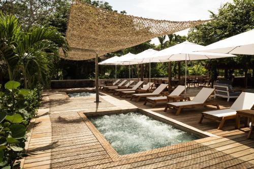 a swimming pool with lounge chairs and umbrellas at Makani Luxury Cartagena in Tierra Bomba