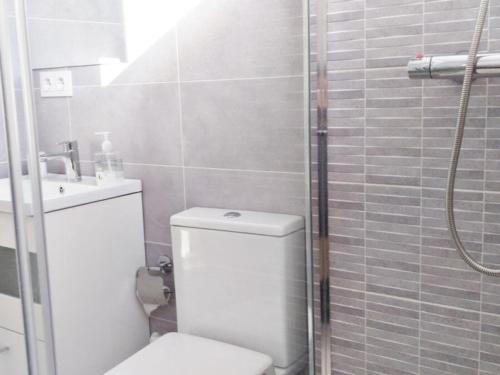 a white bathroom with a toilet and a shower at Apartamentos los Acantilados Nº 1 Cobreces in Cóbreces