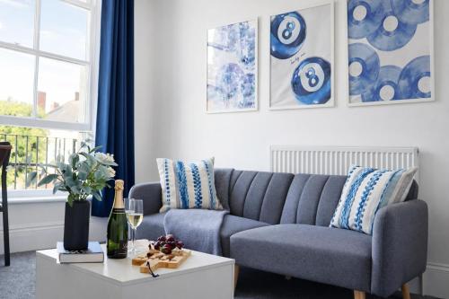 a living room with a blue couch and a table at Modern Serviced Apartments Steps From Gloucester Quays in Gloucester