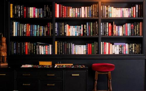 a book shelf filled with lots of books with a stool at The George Inn in Tideswell