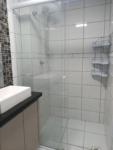 a bathroom with a glass shower with a sink at Jonas e Selma Apartmento 3 quartos in Araucária