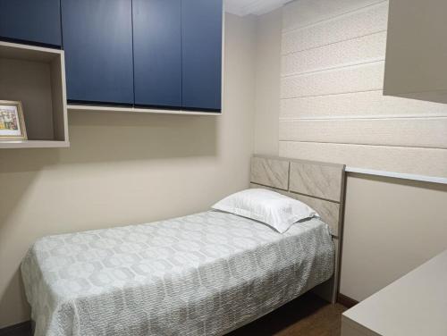 a small bedroom with a bed and blue cabinets at Jonas e Selma Apartmento 3 quartos in Araucária
