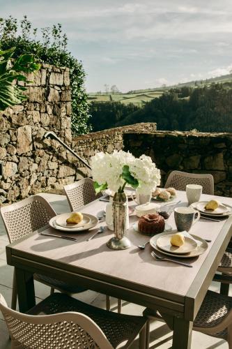 a table with plates of food and flowers on it at Coração da Quinta in Algarvia
