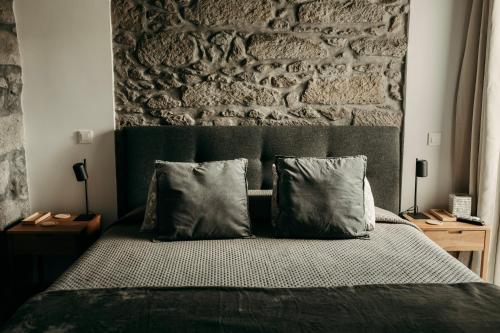 a bedroom with a brick wall and a bed with pillows at Coração da Quinta in Algarvia