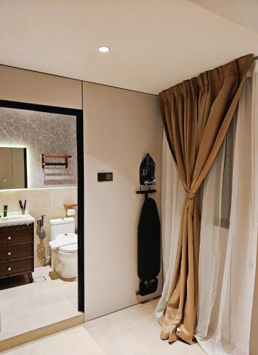 a bathroom with a toilet and a shower curtain at Carnarvon Suites in George Town