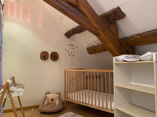 a baby room with a crib and wooden ceilings at Au Pied de Troncais in Coust