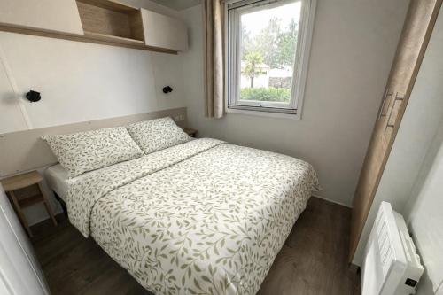 a small bedroom with a bed and a window at Les sables chal’heureux in Saint-Jean-de-Monts