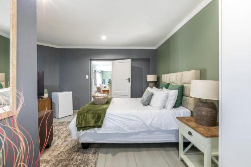 a bedroom with a white bed with green walls at Bella on St James in Johannesburg