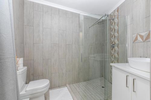a bathroom with a shower and a toilet and a sink at Bella on St James in Johannesburg