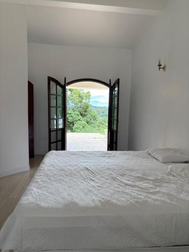 a bedroom with a large white bed with an open doorway at Refúgio em Atibaia in Atibaia