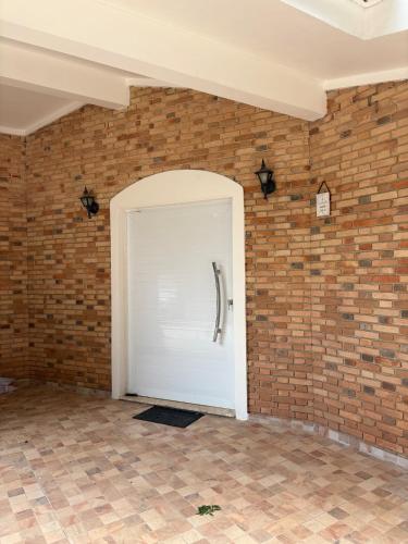 a white door in a brick wall at Refúgio em Atibaia in Atibaia