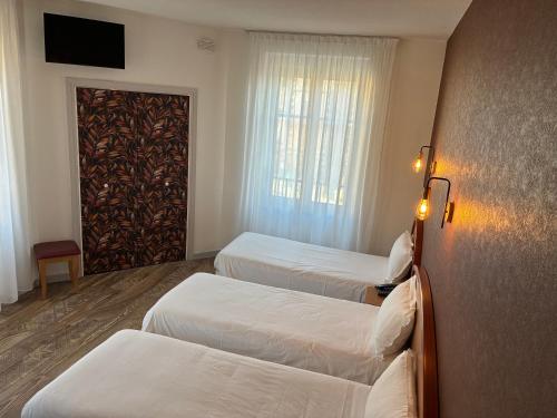 a hotel room with three beds and a door at Logis Hôtel du Commerce in Volvic