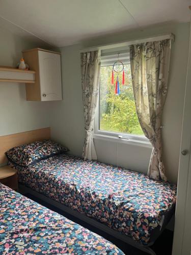 a small bedroom with two beds and a window at Meadow lakes golden palm resort in Chapel Saint Leonards