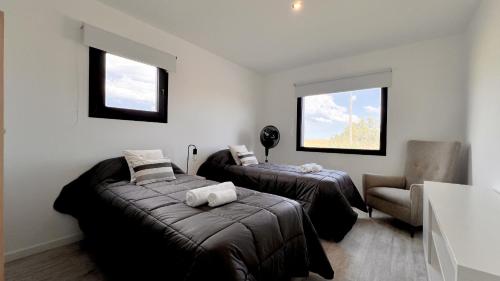 a room with two beds and a chair and two windows at Marea Baja - Casa con vista al mar para 6 PAX con parrilla en Cruz del Sur, Chapadmalal - Hola Sur in Chapadmalal