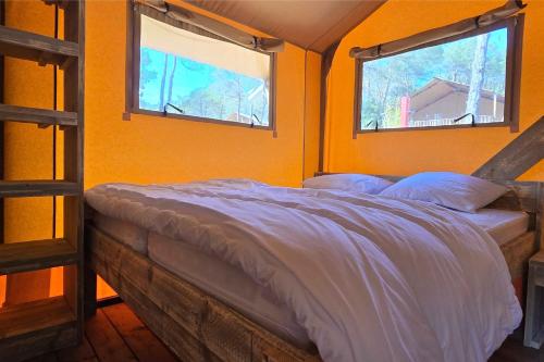 a bed in a room with two windows at Camping Saint-Laurent-du-Verdon in Saint-Laurent-du-Verdon
