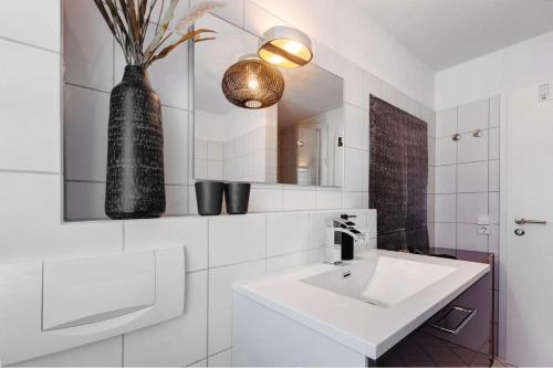 a bathroom with a white sink and a vase on the wall at Fewo SPECTRUM II in Uhldingen-Mühlhofen