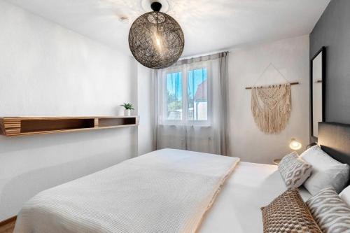 a white bedroom with a bed and a window at Fewo SPECTRUM II in Uhldingen-Mühlhofen