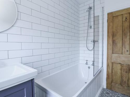 a white bathroom with a tub and a shower at Shipwrights, 11 Coronation Road in Salcombe