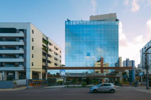 ein Auto fährt vor einem Glasgebäude in der Unterkunft Manaíra Hotel in João Pessoa