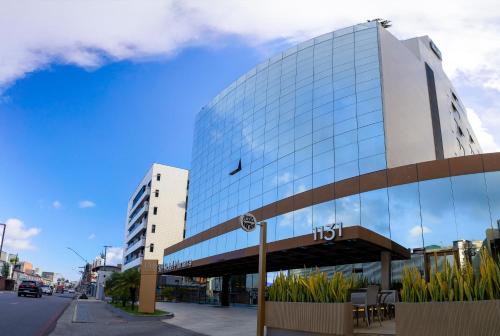 ein hohes Glasgebäude in einer Stadtstraße in der Unterkunft Manaíra Hotel in João Pessoa