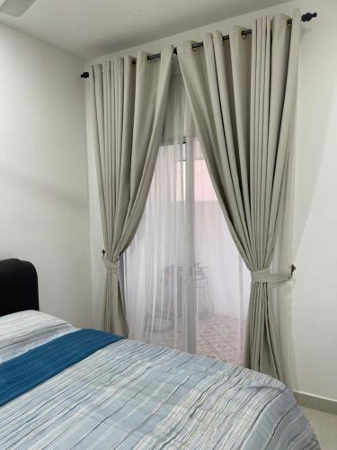 a bedroom with a bed and a window with curtains at Nafisa Homestay in Kepala Batas