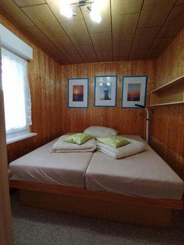 a bed in a wooden room with two pillows at Bungalow am Ferchesarer See in Ferchesar