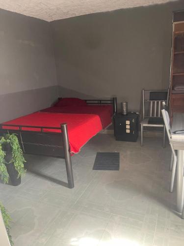 a bedroom with a bed with a red comforter and a chair at Departamento Central Camionera in Guadalajara