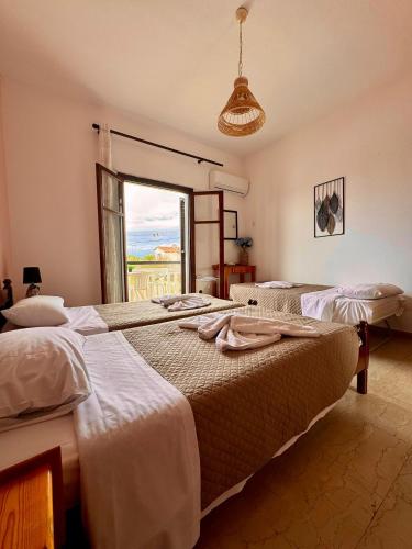 two beds in a room with a window at Tzilios Studios in Acharavi