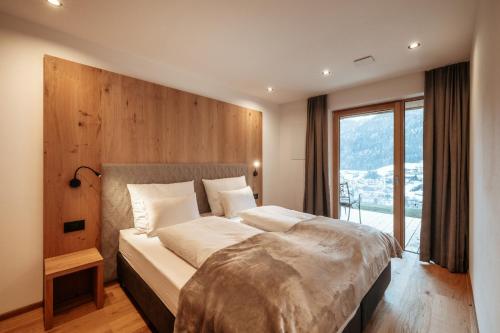 a bedroom with a large bed with a large window at Resciesa Hof in Ortisei