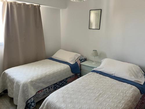 two beds in a small room with a window at Ballenas desde el balcon in Puerto Madryn