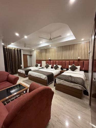a hotel room with three beds and a couch at Hotel Valentines in Prayagraj
