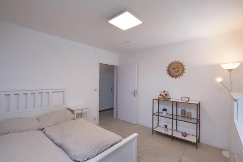 a white bedroom with a bed and a table at Schöne moderne 2-Zimmerwohnung in Göppingen