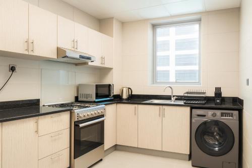 a kitchen with white cabinets and a washer and dryer at Deluxe Apartments Near WTC and Sheikh Zayed in Dubai