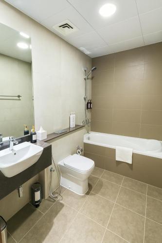 a bathroom with a sink and a toilet and a tub at Deluxe Apartments Near WTC and Sheikh Zayed in Dubai