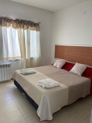 a bedroom with a large bed with two towels on it at Jardines del Liceo in Comodoro Rivadavia